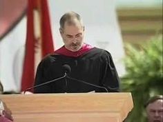 a man standing at a podium in front of a microphone and wearing a black robe