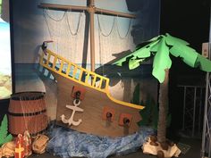 there is a fake pirate ship on display in the room with palm trees and other items