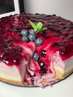 a cheesecake with blueberries and raspberry sauce on the top is ready to be eaten