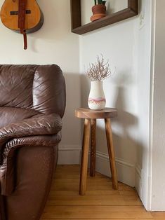 a brown leather couch sitting in a living room next to a table with a guitar on it