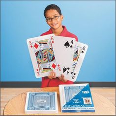 a young boy holding two playing cards on top of a table