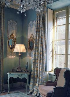 a living room filled with furniture and a chandelier hanging from the ceiling next to a window