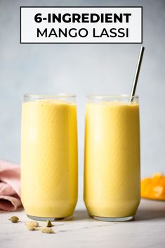 two glasses filled with mango lass sitting next to each other on top of a table