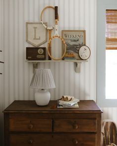 there is a lamp on top of the dresser in this room with striped wallpaper