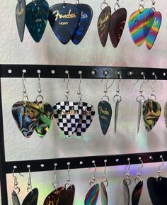 several guitar picks hanging from hooks on a display rack in front of a white wall