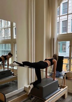 a woman is doing pivots on a machine in front of a window while another person watches