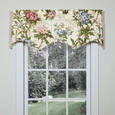 a window with a flowered valance hanging from it's side in front of a lush green yard