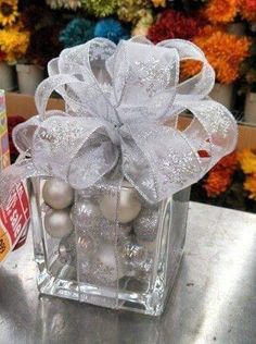 a glass vase with ornaments in it on a table next to some boxes and flowers