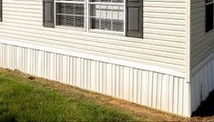 a white mobile home with black shutters and windows