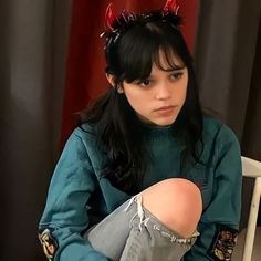 a woman sitting in a chair with devil horns on her head and stockings around her ankles