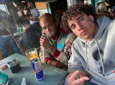 two young men sitting at a table with drinks