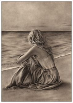 a black and white photo of a woman sitting on the beach looking out at the ocean