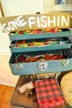 an old suitcase filled with gummy bears sitting on top of a wooden table next to a sign that says gone fishin