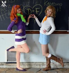 two women dressed in costumes standing next to a chalkboard