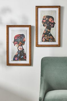 two framed pictures hang on the wall next to a green chair in a living room