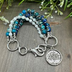 This stunning five strand gemstone bead bracelet is handcrafted with genuine Blue Teal Imperial Jasper round and nugget stones, and tiny Green Moonstone beads, along with silver finish accents, and a large lobster claw clasp, and a Tree of Life charm.  Only high quality genuine stones are used in each unique piece.  This bracelet measures approximately 6.75 inches long.  Sorry - sizing is NOT available on this style. Please message me for special orders.  Imperial Jasper: a spiritual healing stone; encourages tranquility and relaxation; helps with inner peace and stability Green Moonstone: a stone of the goddesses; connects with feminine earth energy; encourages insight Turquoise Multi-strand Gemstone Beads Bracelets, Spiritual Multi-strand Hand Wrapped Beaded Bracelets, Multi-strand Beaded Healing Jewelry, Spiritual Multi-strand Healing Jewelry, Multi-strand Natural Stone Bracelets As Gift, Multi-strand Natural Stone Bracelets For Gifts, Multi-strand Natural Stones Bracelet For Gifts, Multi-strand Beaded Bracelets With Natural Stones As Gift, Spiritual Multi-strand Gemstone Beaded Bracelets