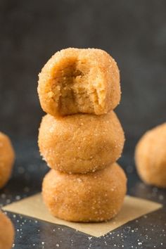 some sugared doughnuts stacked on top of each other with one bite taken out