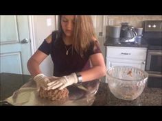 a woman in black shirt and white gloves preparing food on counter top next to oven