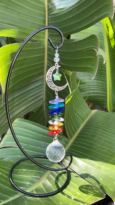 a wind chime hanging from a metal stand on top of a leafy plant