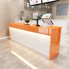 an orange and white counter with two monitors on it's wall above the counter