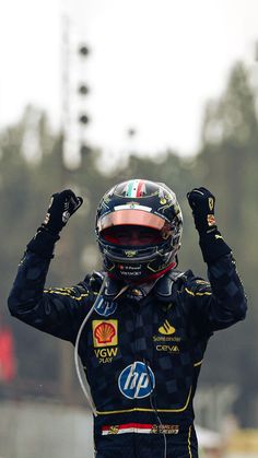 a man in a racing suit holding his hands up