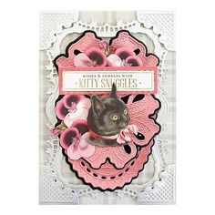 a card with a black cat and pink flowers in the center, on top of a lace doily