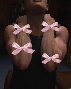 a woman with her arms crossed and pink bows on her chest