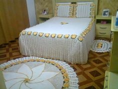 a white bed with yellow flowers on the bedspread and matching round rugs