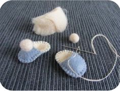 two pieces of felt are sitting on the floor next to some knitting needles and yarn balls