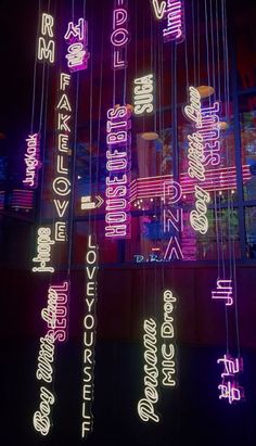 neon lights are hanging from the ceiling in front of a building with words written on it