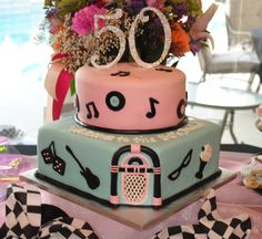 a cake that is sitting on top of a table with flowers and ribbons around it