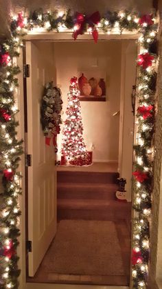 an entry way decorated for christmas with lights and garlands on the door, and a small tree in the doorway