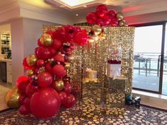 a room decorated with red, gold and white balloons