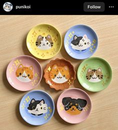 six small plates with cats painted on them sitting on a table top next to each other