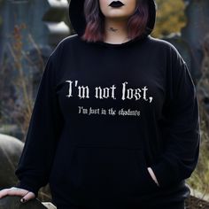 Gothic Hoodie with a funny Goth Quote on the front: I'm not lost, I'm just in the shadows. This black Spooky Hoodie creates a dark gothic and witchy style.  Fun for a Halloween lover, Gothic or Sarcastic Person. ❗️❗️❗️Please be aware that the  Hoodie is an Unisex Cut and may be oversized.  Please check the size charts to measure yourself to be sure you will receive a good sized item. ❗️Please check the size before ordering.  All our products are print on demand,  to reduce the amount of unnecess Black Gothic Hoodie For Fall, Black Gothic Hoodie For Cosplay, Cozy Goth Outfit, Gothic Cotton Hoodie For Alternative Fashion, Witchy Clothes Aesthetic, Comfy Goth Outfits, Emo Hoodie, Witchy Hoodie Ideas, Black Gothic Hoodie Sweatshirt