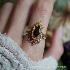 a woman's hand wearing a gold ring with an oval black stone on it