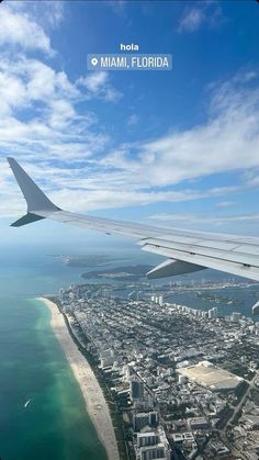 an airplane wing flying over the ocean and cityscape in miami, florida on a sunny day