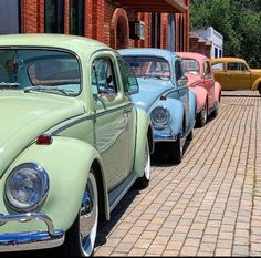 several old cars are lined up on the side of the road in front of a brick building