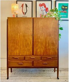 a wooden cabinet with two doors and three drawers on the front, sitting against a wall