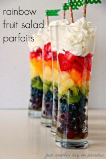 rainbow fruit salad parfaits in clear cups with green trees on top and white frosting