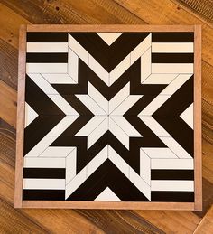 a black and white tile pattern on a wooden floor with wood planks in the background