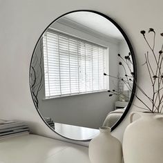 a mirror sitting on top of a table next to a vase