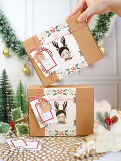 two boxes with christmas greeting cards are being held by someone's hand and tied together