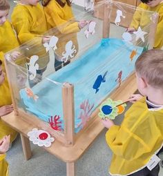 children in yellow raincoats looking at an aquarium