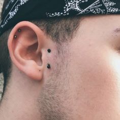 a close up of a man's ear with small black dots on it