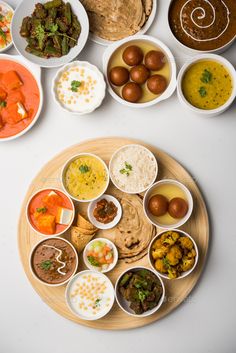 an overhead view of several different types of food in small bowls on a wooden plate