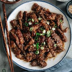 a white plate topped with meat next to chopsticks