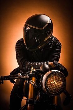 a man in a leather jacket and helmet sitting on a motorcycle with his hands on the handlebars