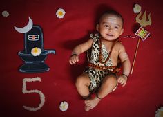 a baby sitting on the floor next to a number five with flowers and decorations around it