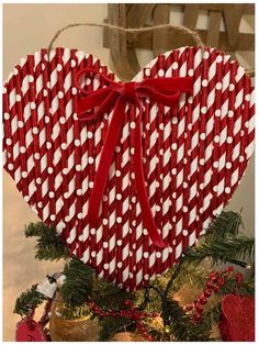 a red and white heart shaped ornament hanging from a christmas tree with ribbon